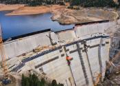 Dam with reservoir behind it and construction equipment in place